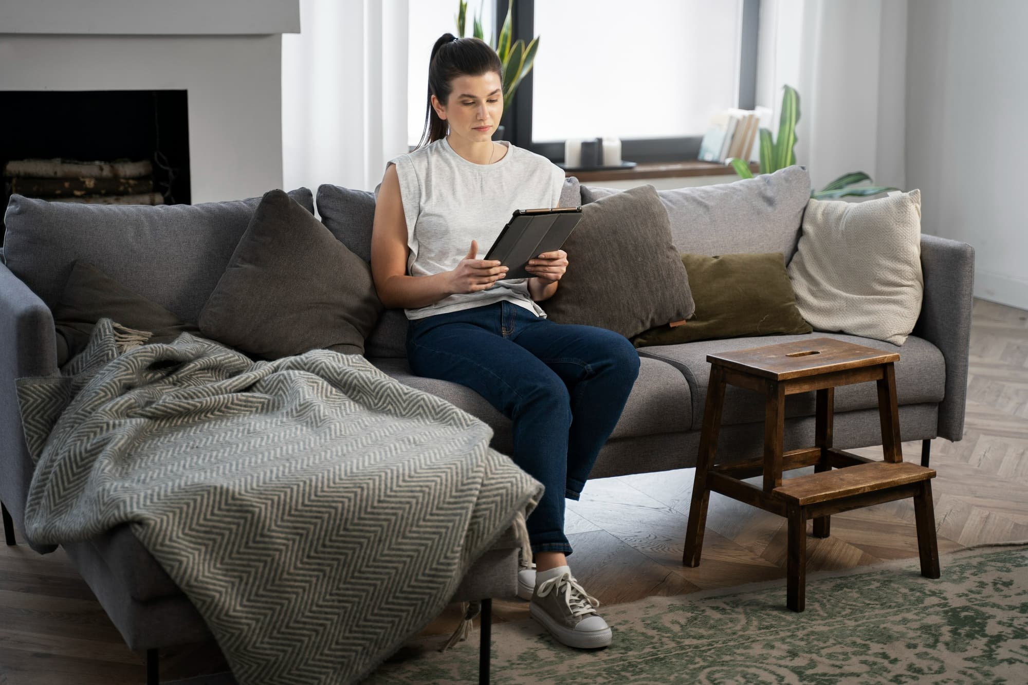 Woman sitting on a couch reviewing information on a tablet